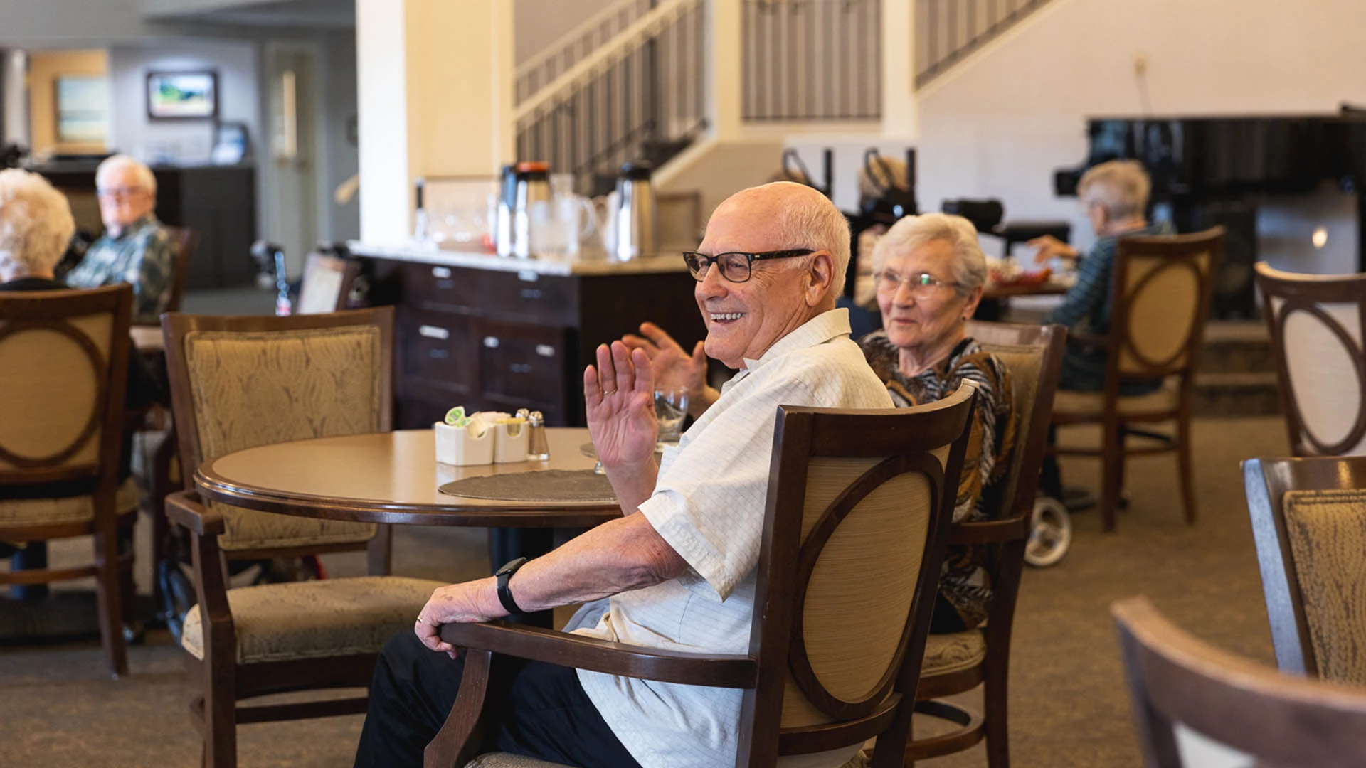 Senior couple sitting at a table waving