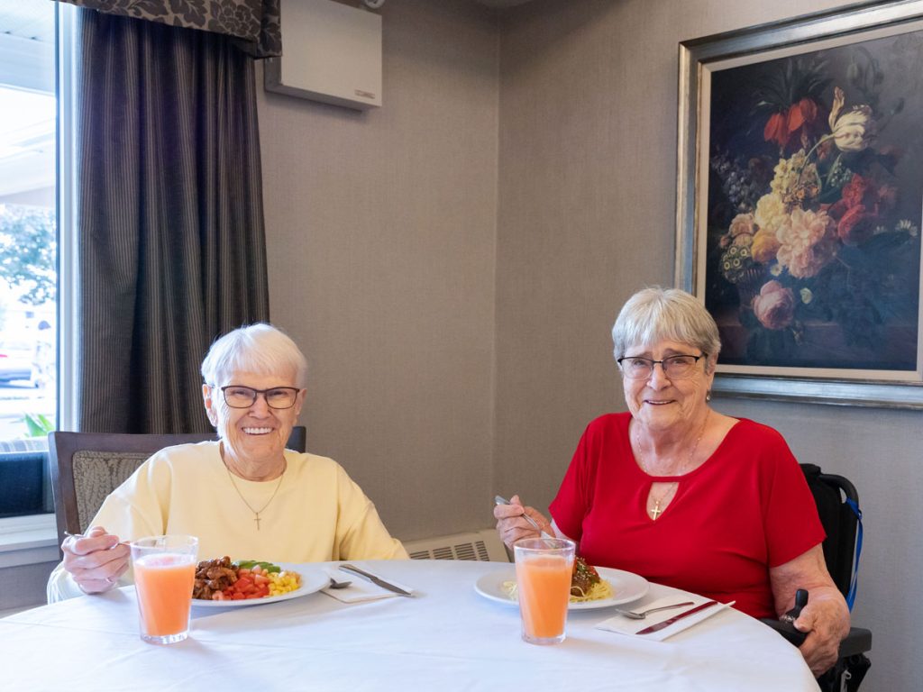 two smiling residents enjoying meal